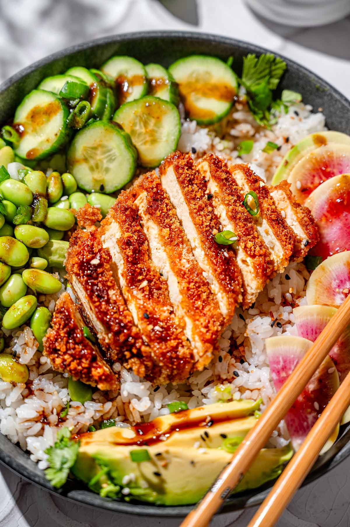 sliced panko breaded katsu tofu on a sushi bowl.