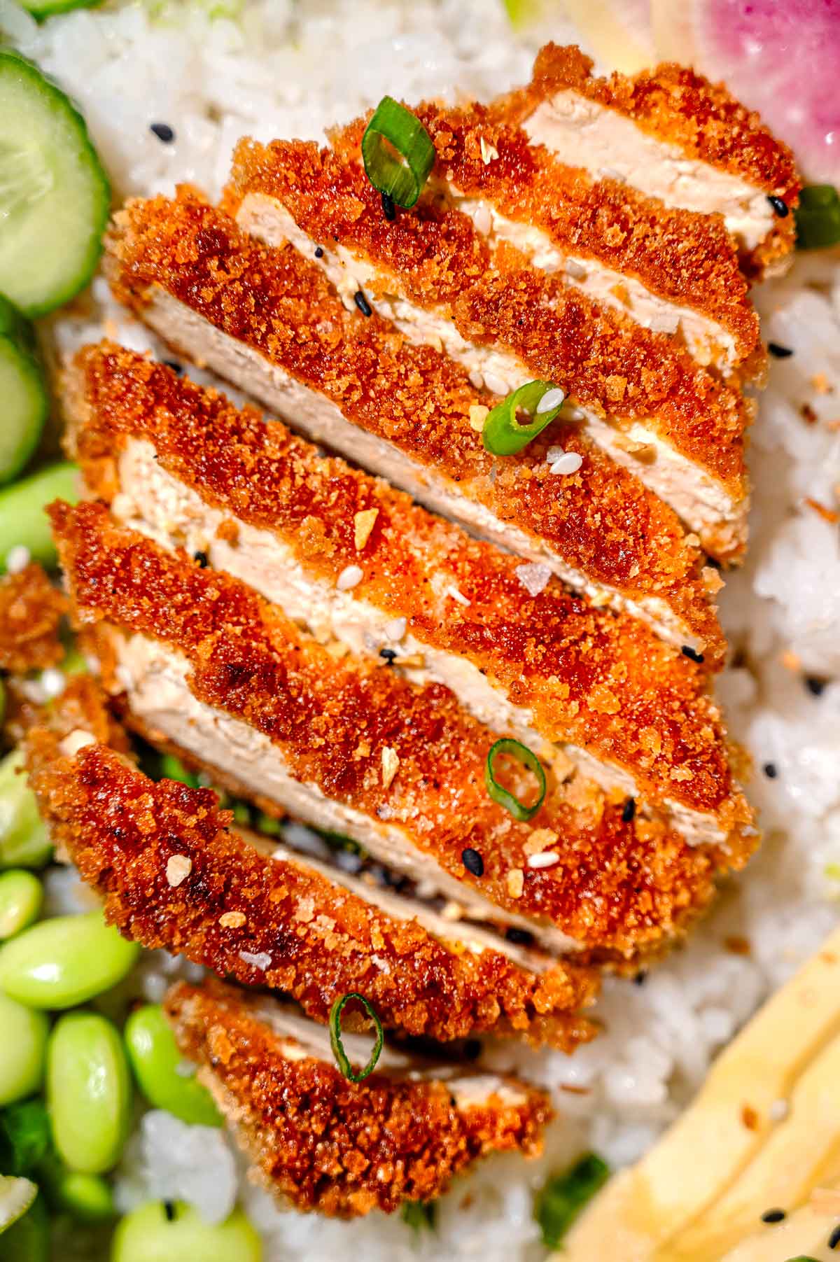 Sliced crispy panko tofu served over white rice with cucumber, edamame, avocado, scallions, and sesame seeds.
