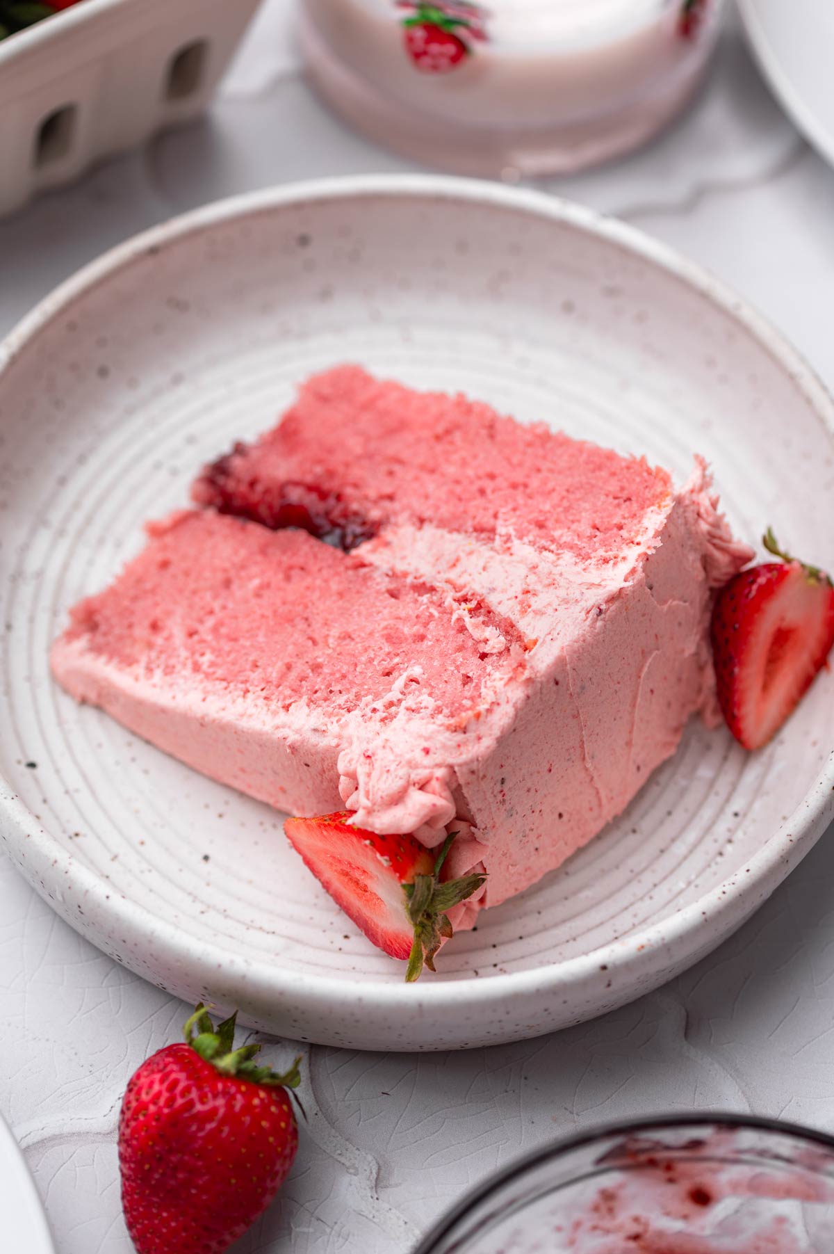 a slice of vegan strawberry cake with jam filling and a strawberry frosting.