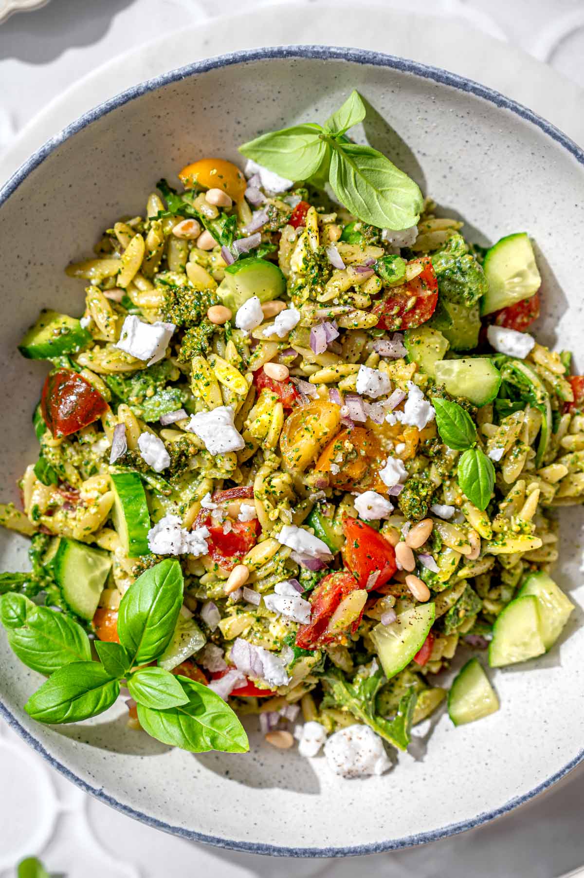 the pesto orzo with cherry tomatoes and vegan feta in a serving bowl.