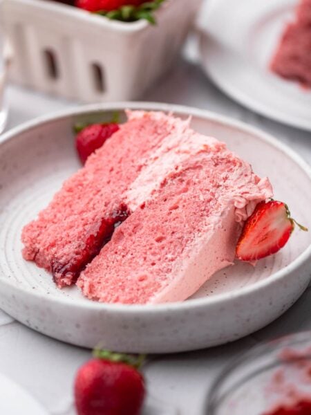a slice of vegan strawberry cake with strawberry buttercream and jam filling.