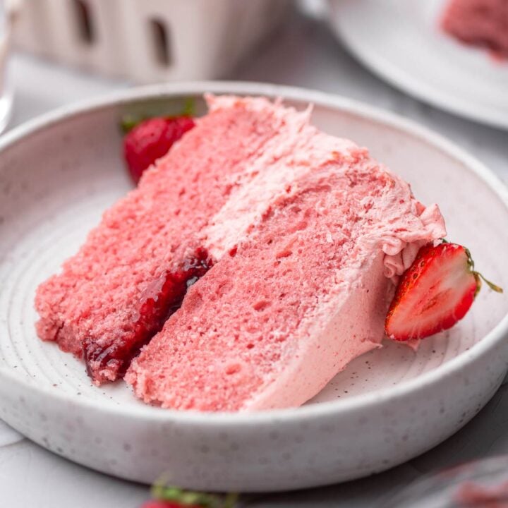 a slice of vegan strawberry cake with strawberry buttercream and jam filling.