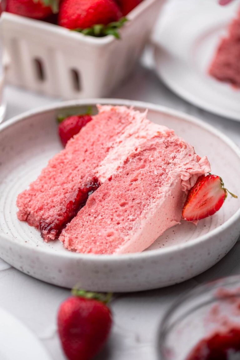 a slice of vegan strawberry cake with strawberry buttercream and jam filling.