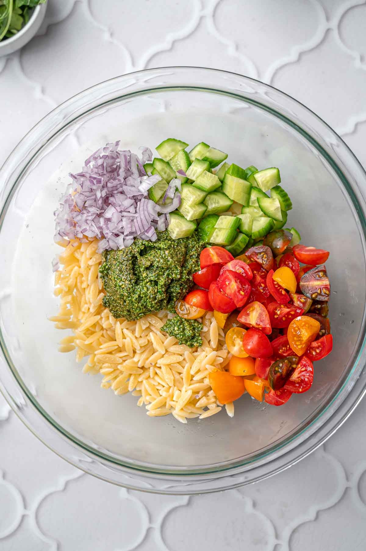 cooked orzo, veggies and pesto in a bowl.