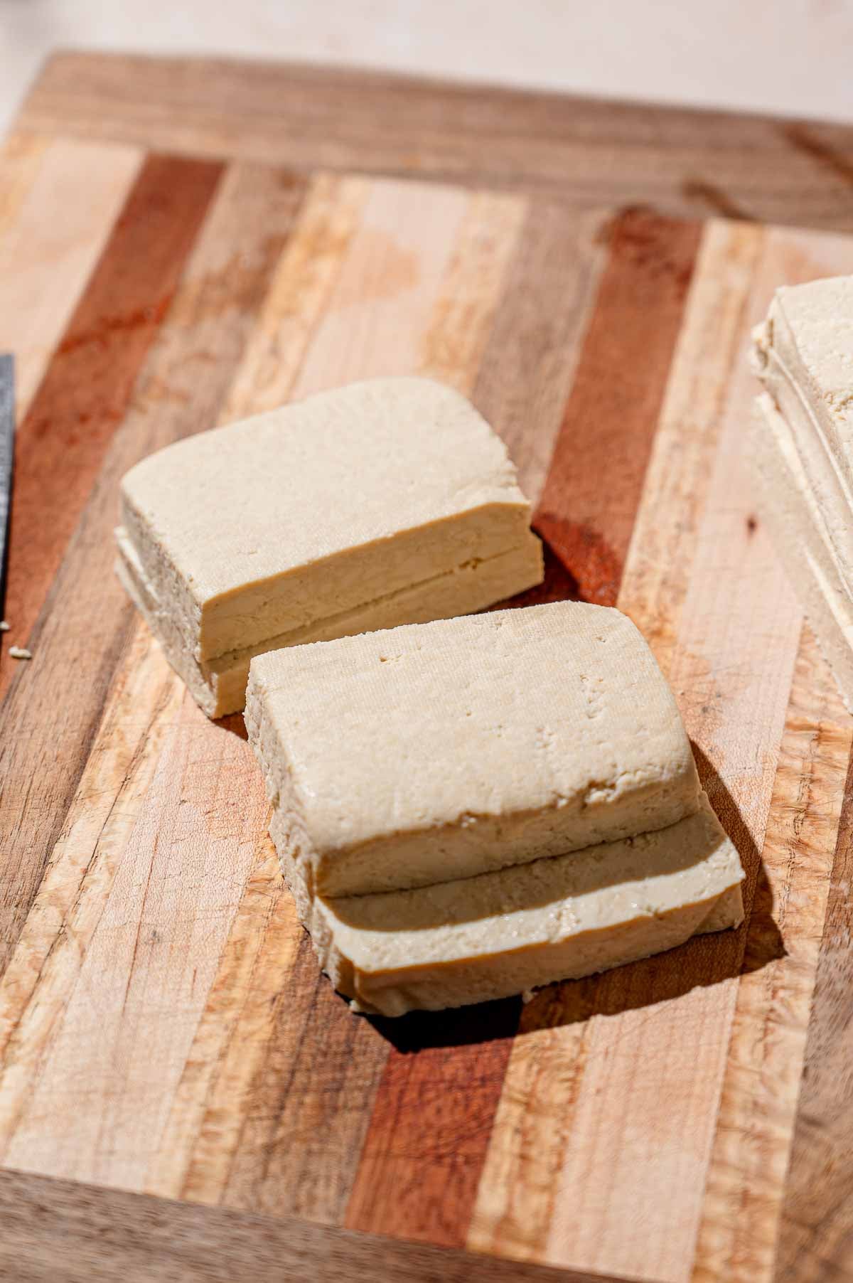 rectangles of super firm tofu on a wood cutting board.