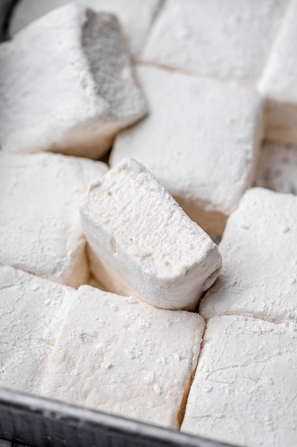 Fluffy homemade vegan marshmallows cut into squares and dusted with powdered sugar.