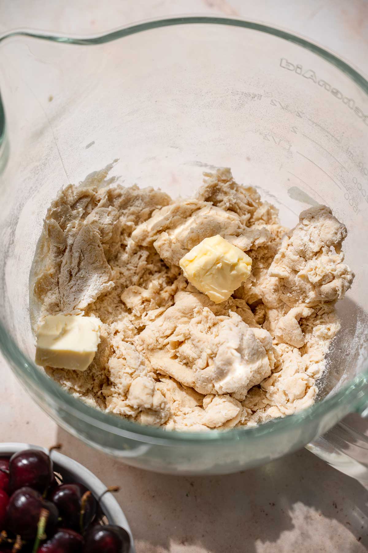 scraggly dough with pats of softened vegan butter in a glass stand mixer bowl.