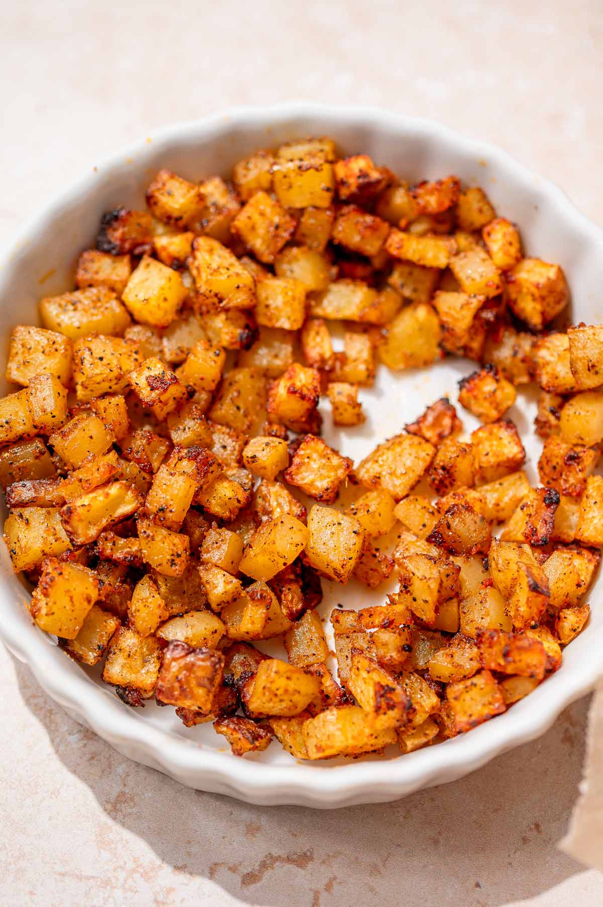 Crispy seasoned potatoes in a white dish for filling vegan chorizo tacos.