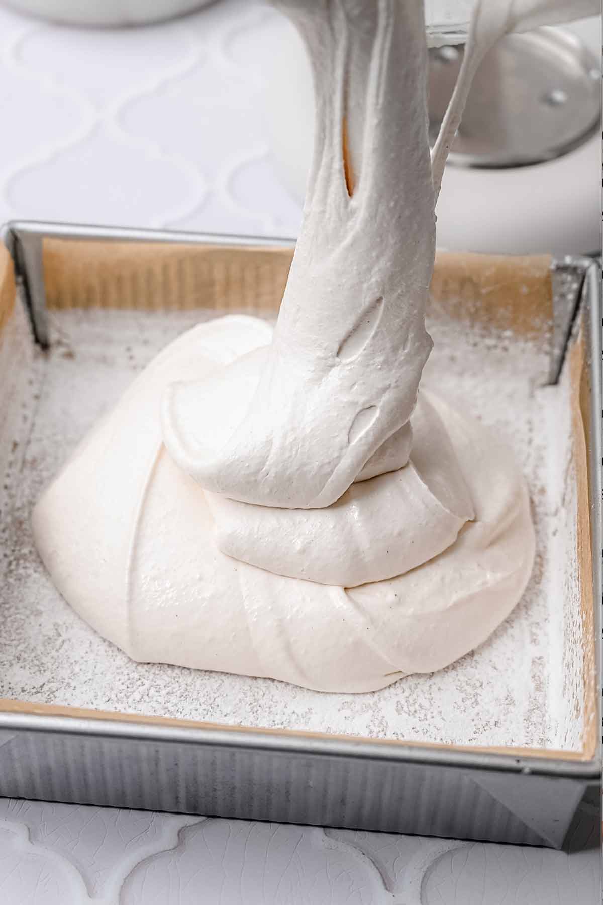 the marshmallow being poured into a prepared pan.