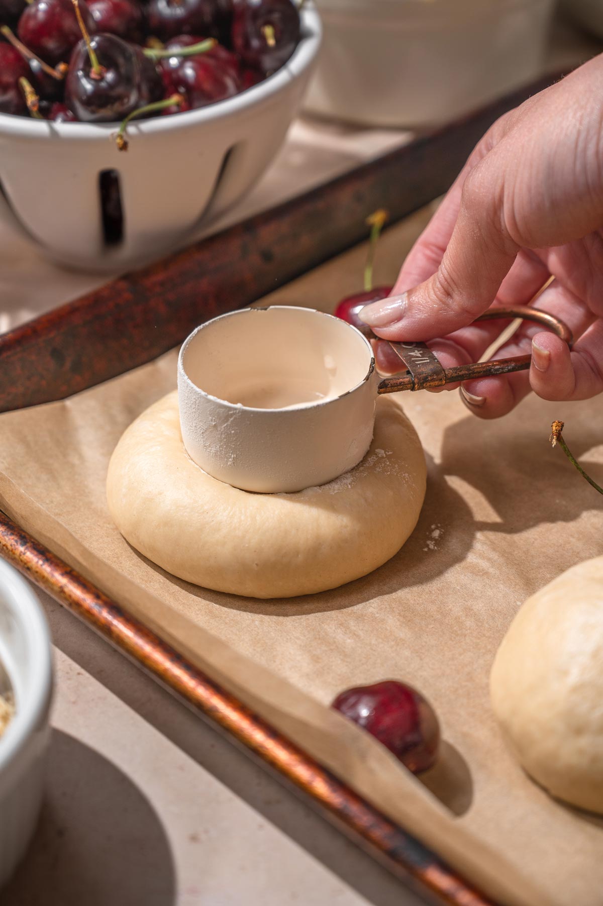 a hand pressing the dough down with a white measuring cup.
