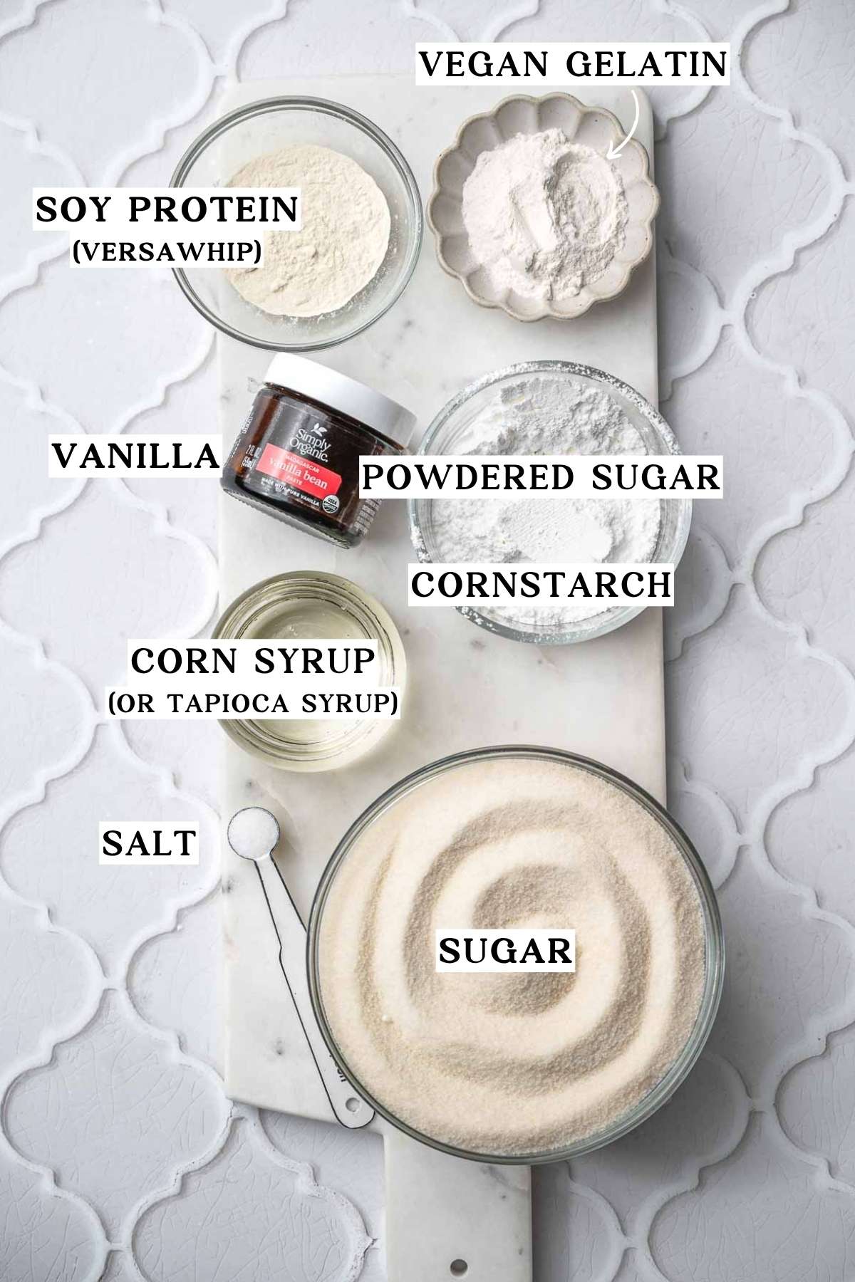 ingredients like corn syrup, sugar, vanilla paste, vegan gelatin and soy protein on a marble tray.