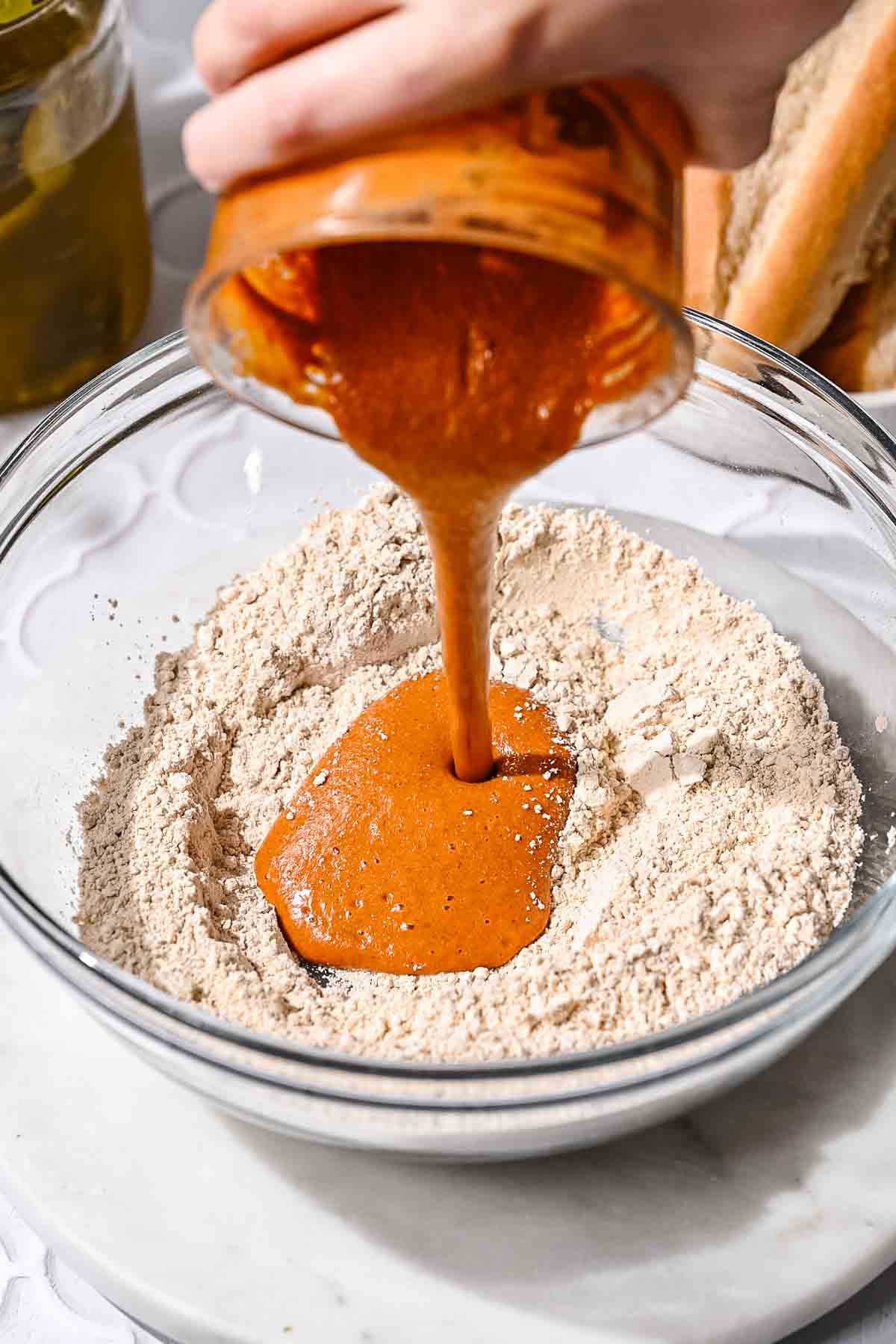 Blended wet ingredients being poured into vital wheat gluten to make seitan.