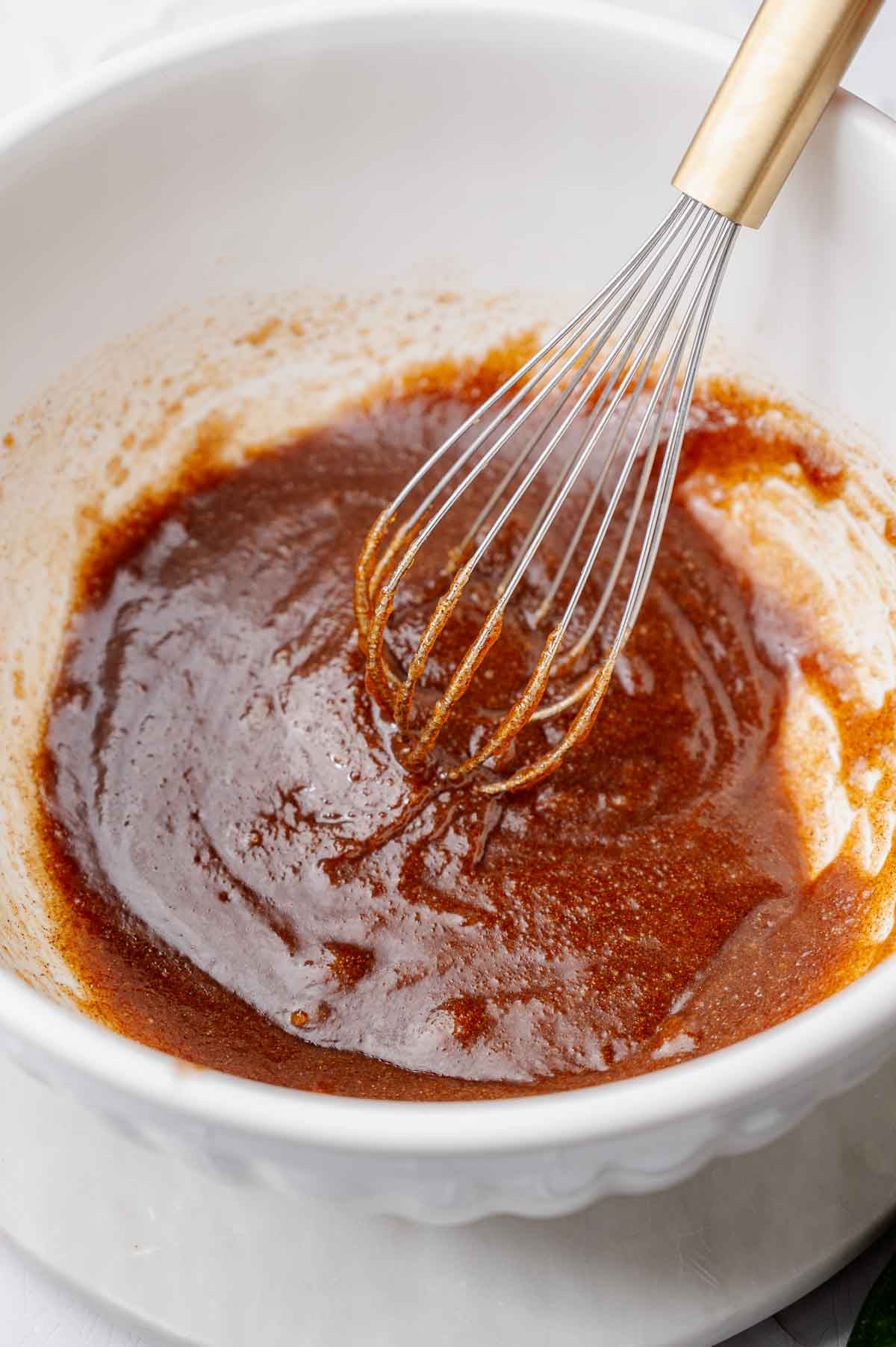 Wet ingredients for vegan zucchini bread whisked together in a large white mixing bowl.