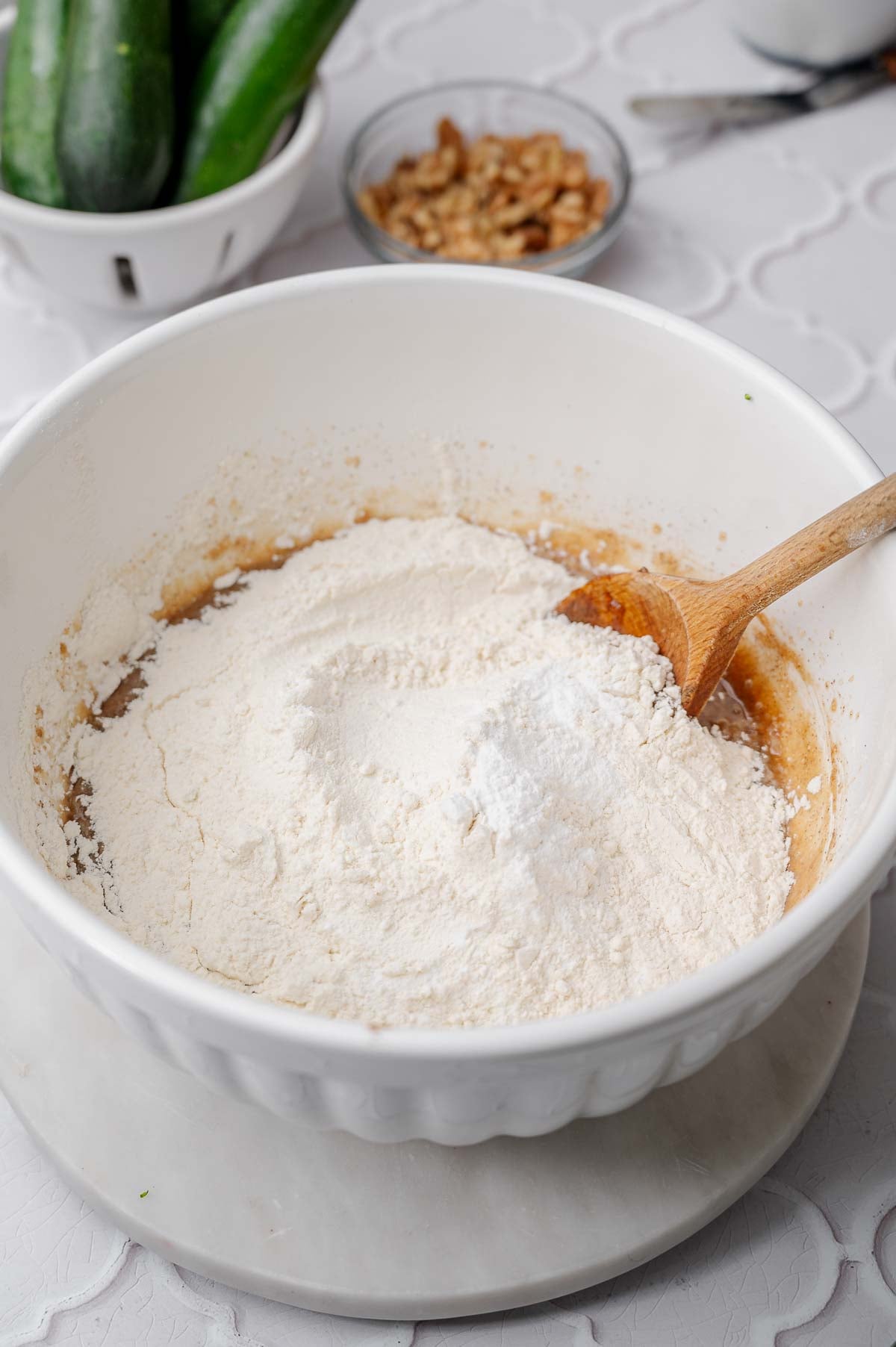 Flour, baking soda and baking powder added to the wet ingredients for vegan zucchini bread.