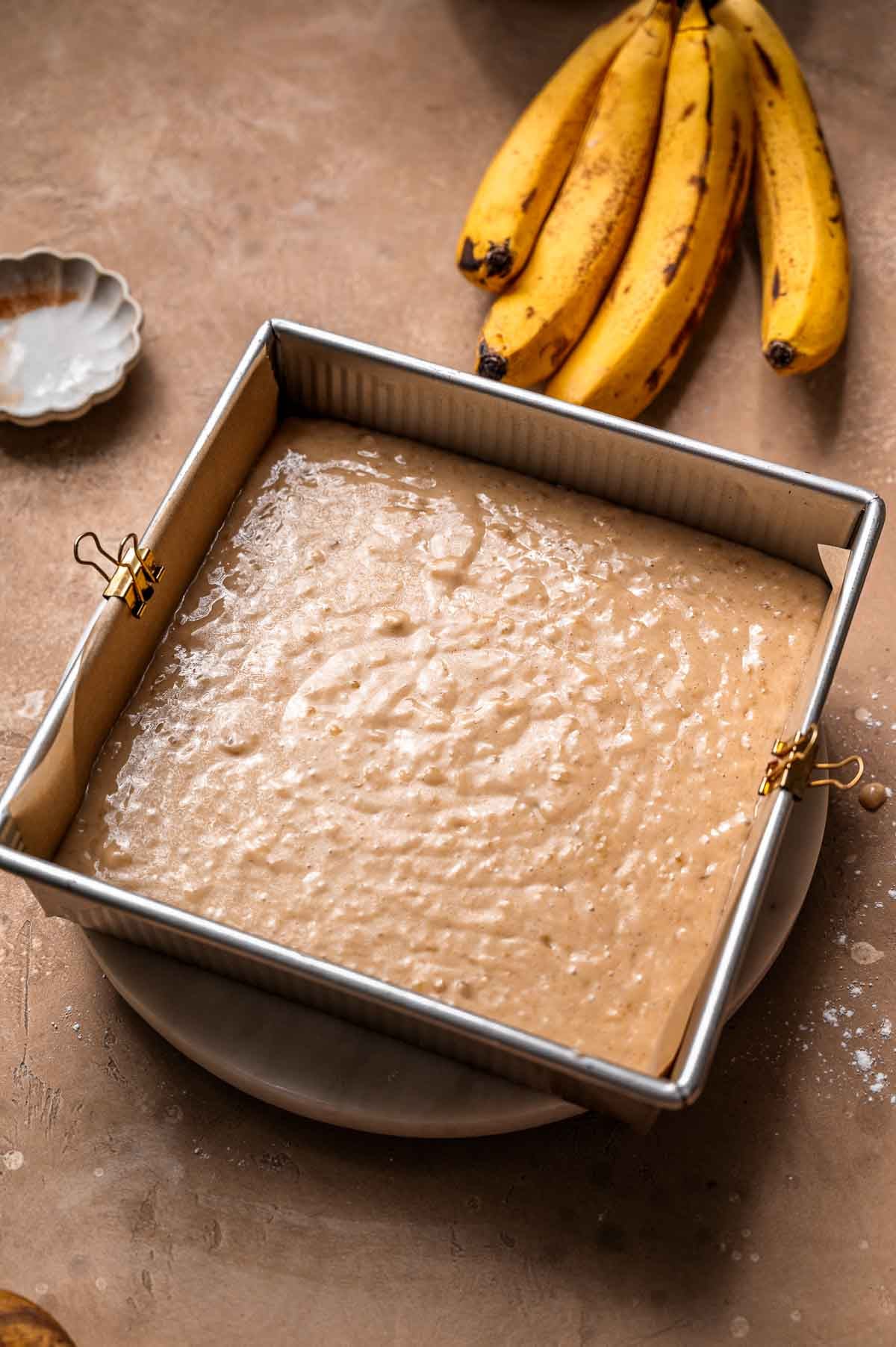 The cake batter in a square metal baking pan.