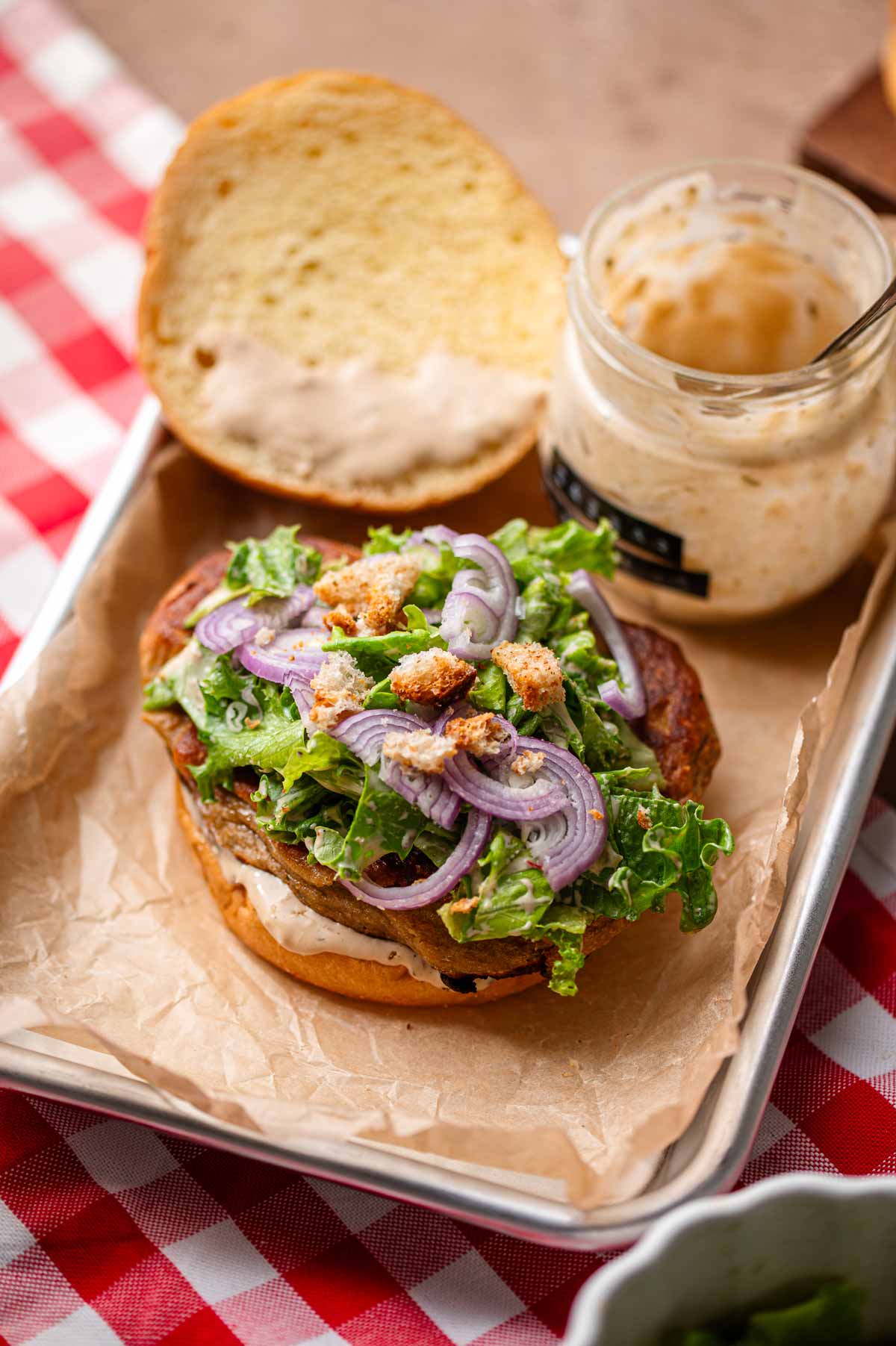 an open face sandwich with vegan chicken topped with caesar salad.