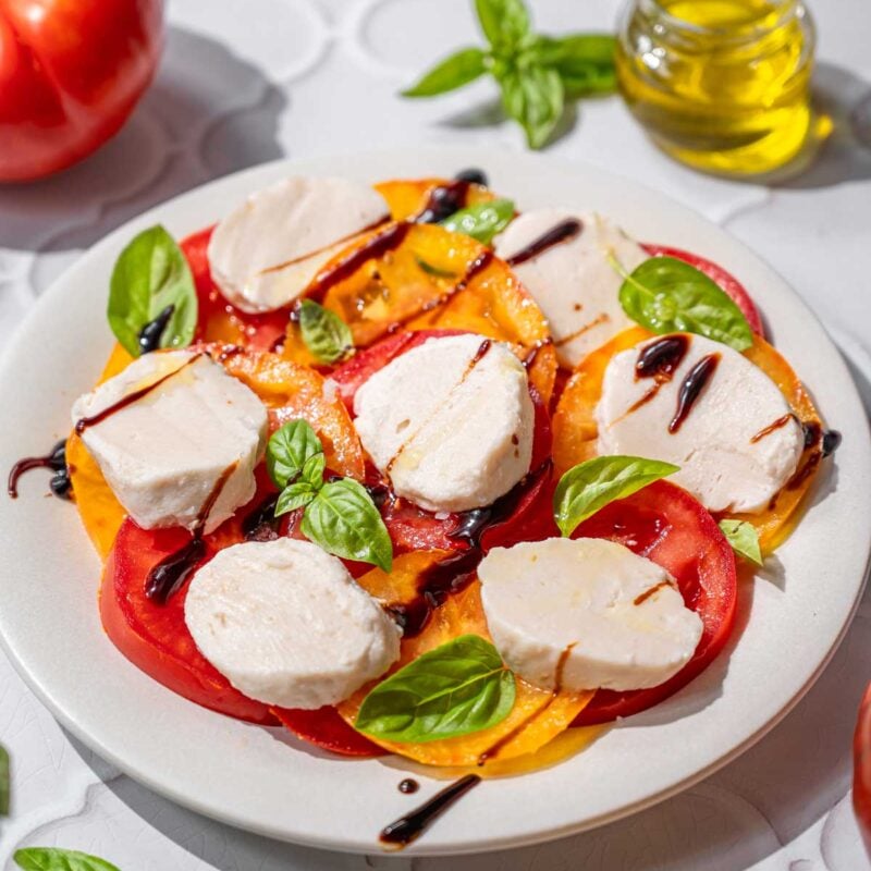 vegan caprese salad on a plate with balsamic drizzle.