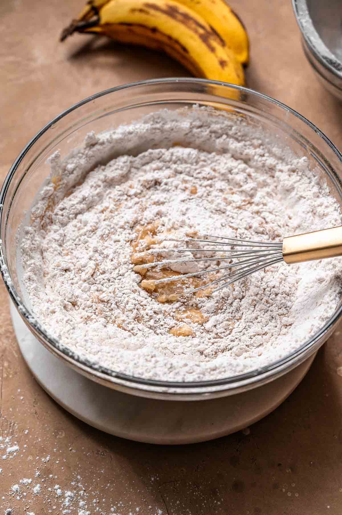 Dry ingredients being whisked into the wet mixture for vegan banana cake.