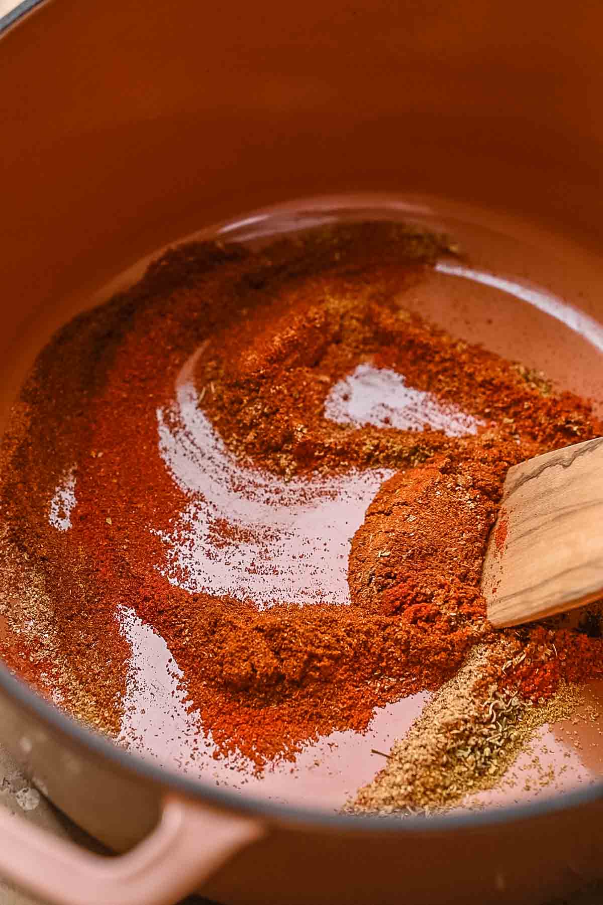 dry chili spices like chili powder, cumin and cayenne dry roasting in a dutch oven.