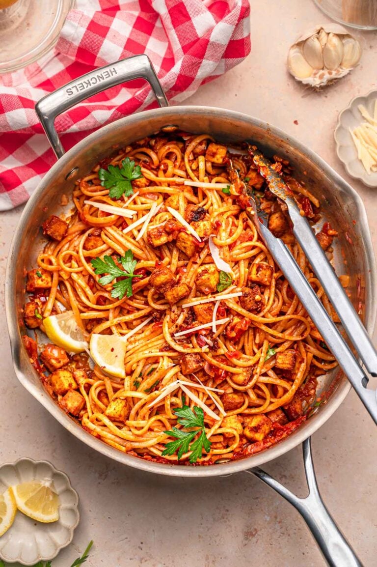 Vegan linguine with paprika tofu and chili flakes in a stainless steel pan.