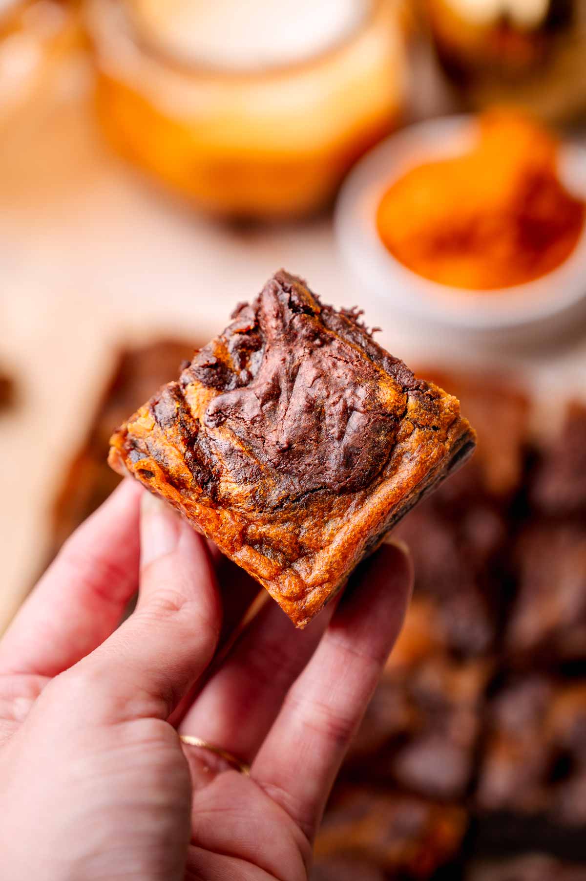 a hand holding a vegan pumpkin swirl brownie.
