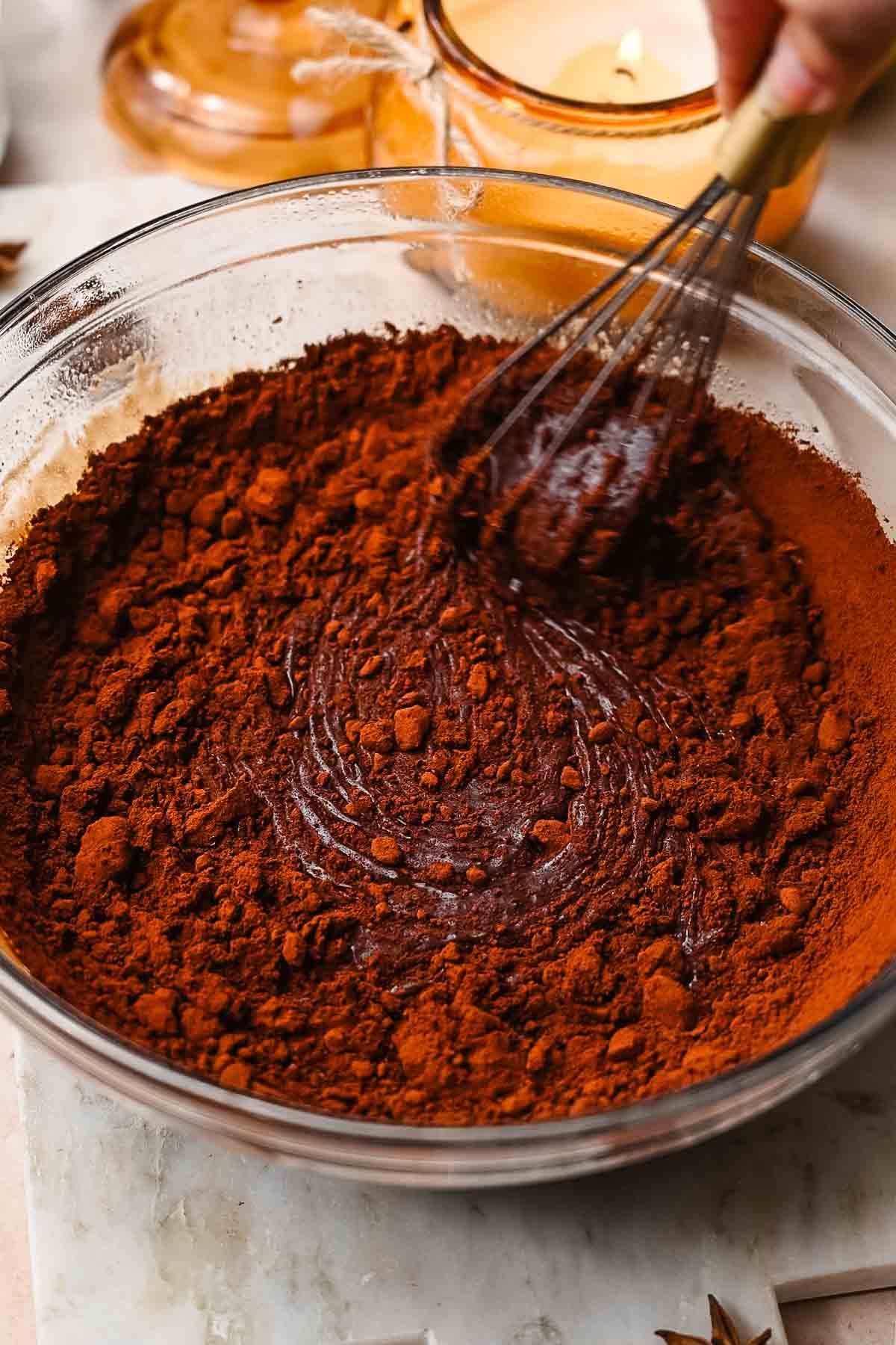 a hand whisking cocoa powder into the batter.