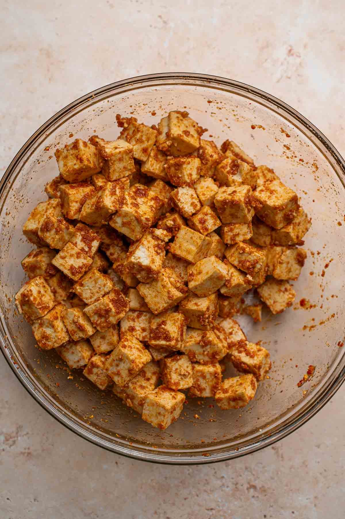 seasoned super firm tofu in a glass mixing bowl.