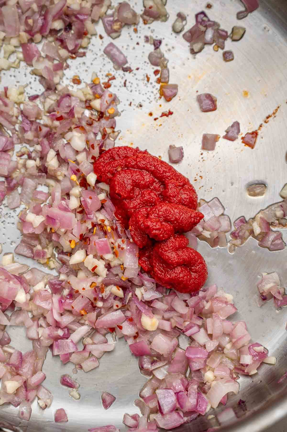 minced onion and garlic with tomato paste in a pan.