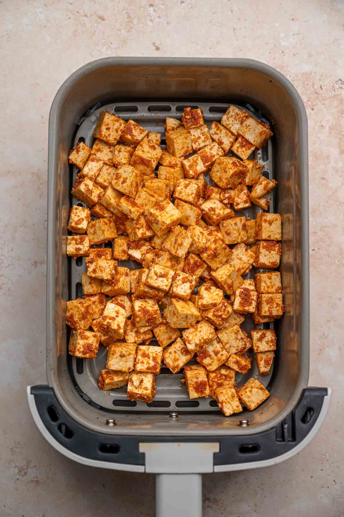 Seasoned paprika tofu in an air fryer basket.