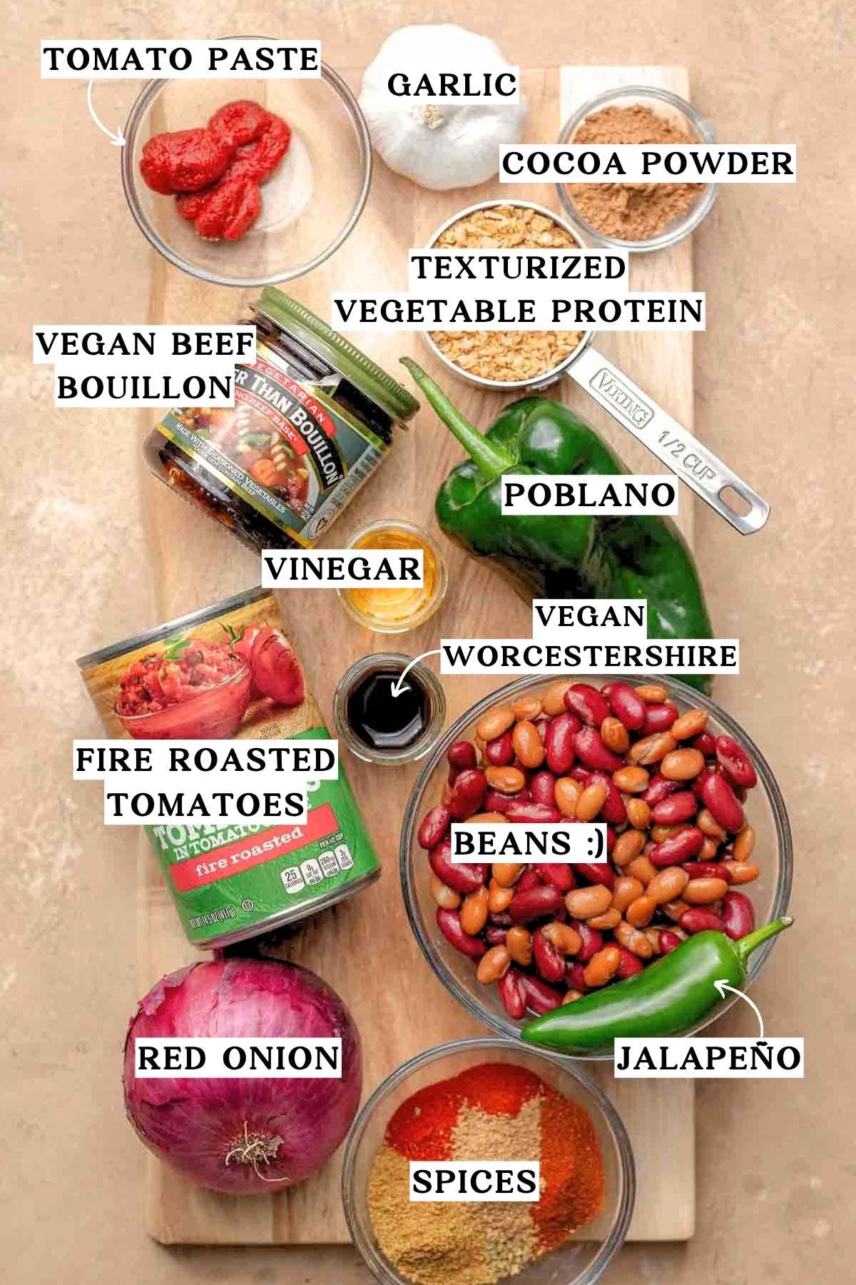 ingredients like TVP, fire roasted tomatoes, beans, onion and vegetarian beef bouillon on a wood cutting board.
