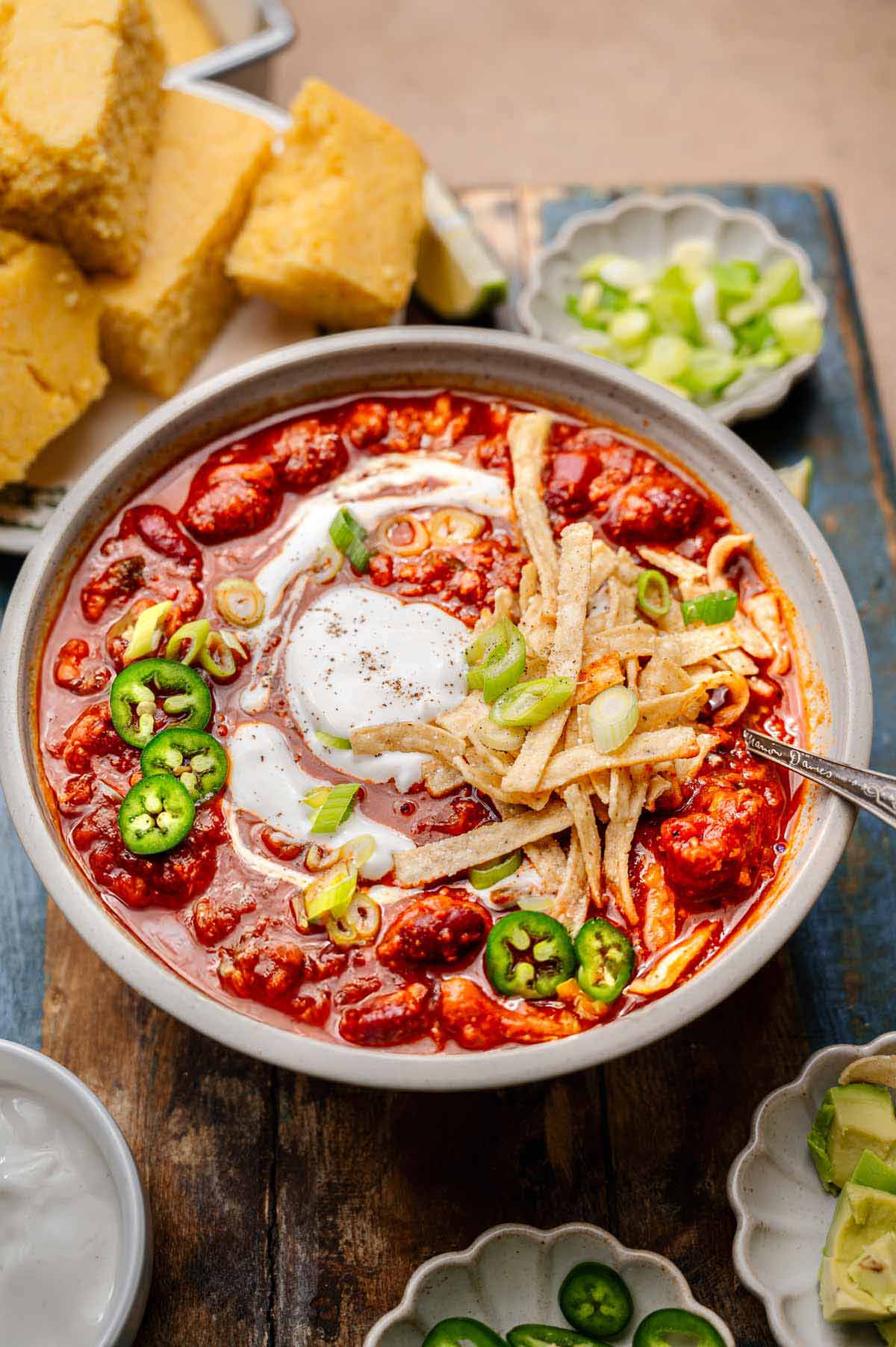a bowl of vegan and vegetarian chili made with TVP with a stack of cornbread behind it.