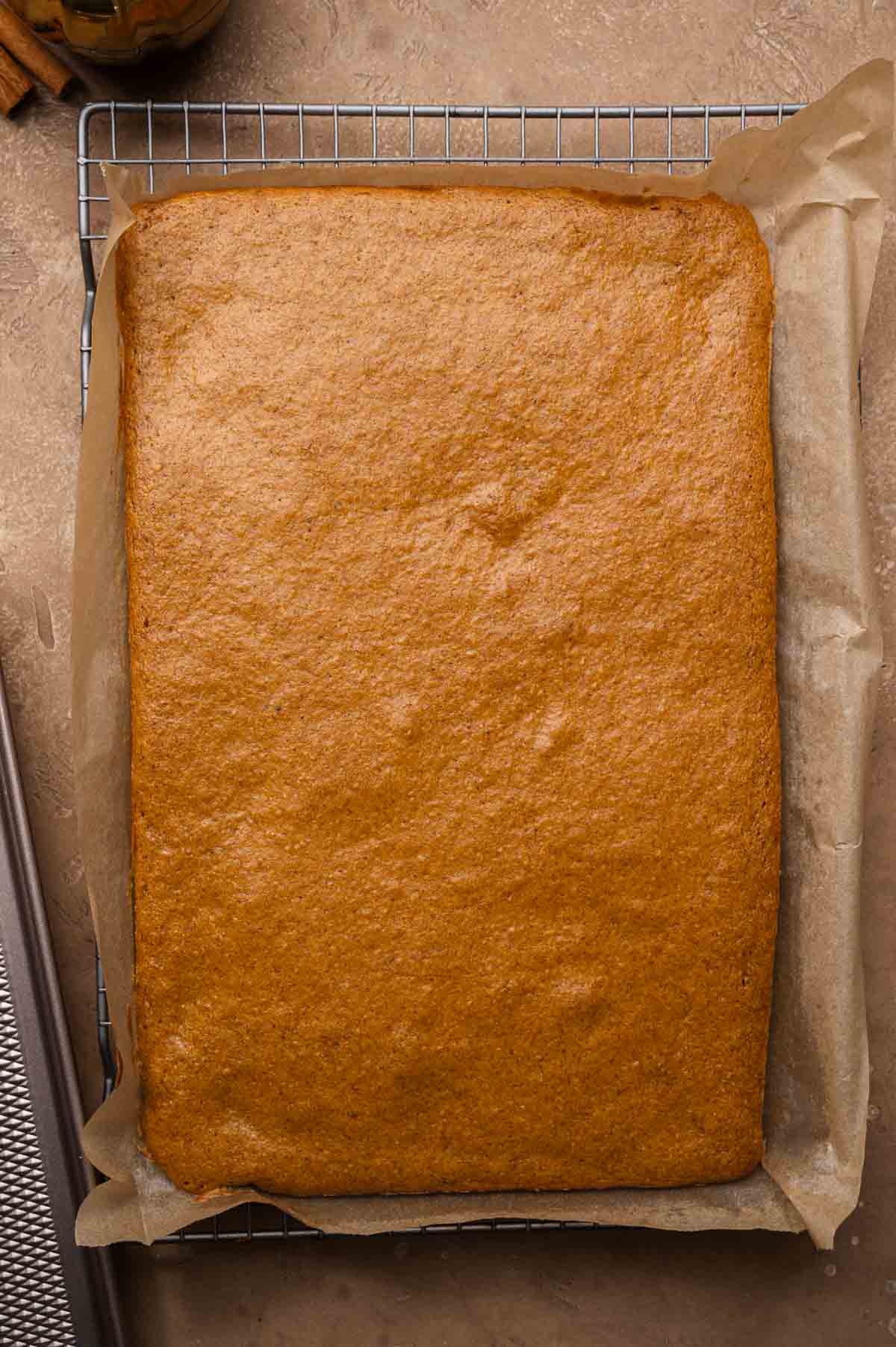 Golden-brown pumpkin sheet cake baked evenly in a parchment-lined rectangular pan.