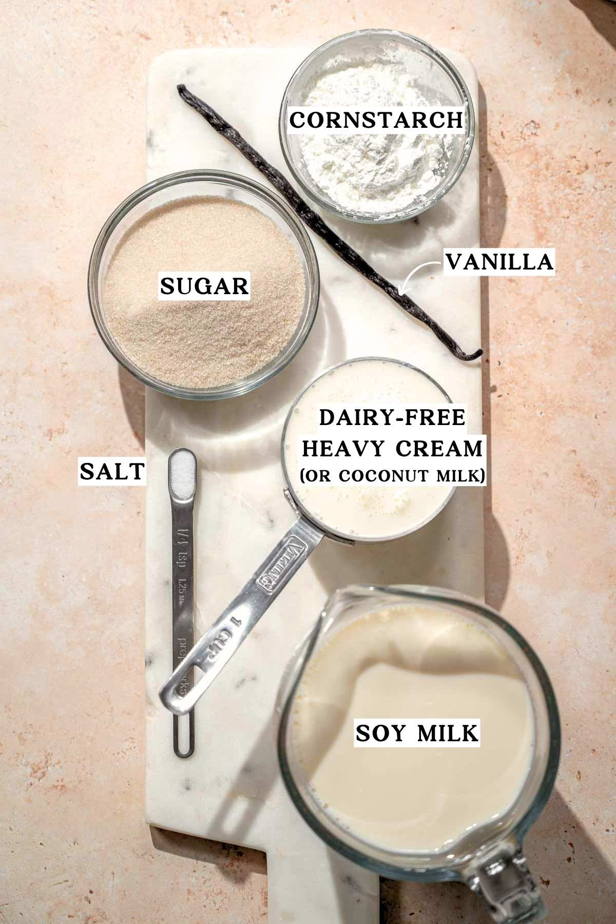 Overhead view of ingredients: soy milk, dairy-free heavy cream, sugar, cornstarch, salt, and vanilla bean.